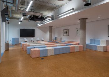 Industrial style interior at Consensys office auditorium style room with screen and pastel fabric cube seats