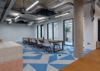 Break out area at Consensys office Large and open office break out space with long dining table and blue and white geometric floor