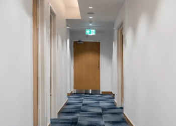 Corridor at Olympia Henley Suite corridor with white walls and dark blue geometric pattern carpet