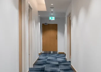 Corridor at Olympia Henley Suite corridor with white walls and dark blue geometric pattern carpet